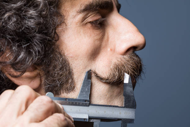 istock Adult Man Measures Handlebar Mustaches With Vernier Calliper 1057730536