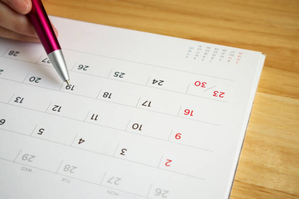 istock calendar page with female hand holding pen on desk table 1057734420