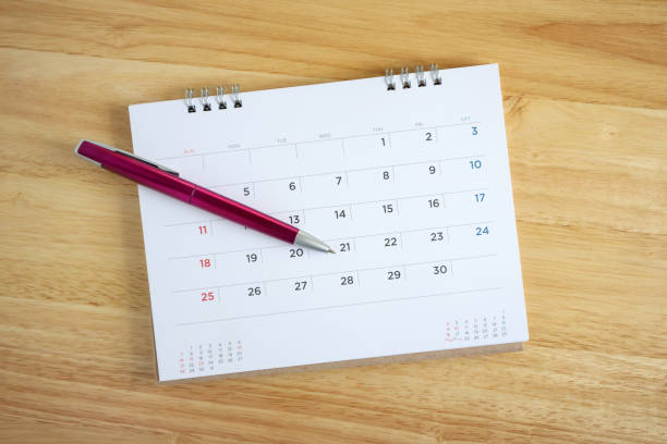 istock Calendar page with pen on wooden desk table 1057734714