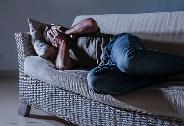 istock young desperate sad and frustrated man lying low at home sofa couch suffering depression problem and anxiety crisis crying helpless in pain feeling sick and unwell on dramatic light 1057744456