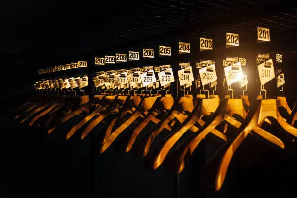 Wooden hangers with numbers in dark cloakroom.