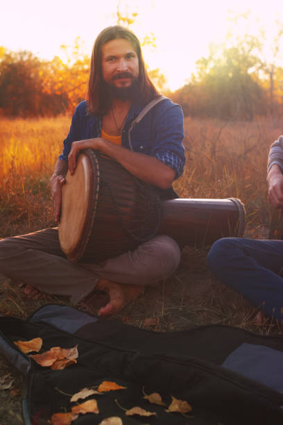 istock Hippie man playing djembe drum in autumn forest. 1057759922