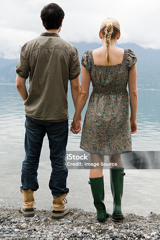 Giovane Coppia in piedi dal Lago con le mani - Foto stock royalty-free di Gruppo multietnico