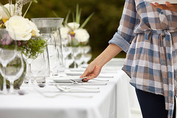 Woman preparing table for dinner party in a field  place setting table plate dining table stock pictures, royalty-free photos & images