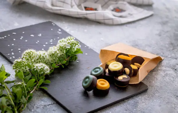 Raw candies for people who love sweets. Its contain just natural ingredients, sugar, cacao powder, cacao butter. Beautiful and delicious raw vegan candies on grey background.