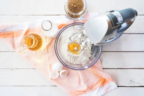 Mixing flour and eggs with a table mixer, ingredients on the table