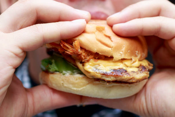 istock Man eating a hamburger, close-up, unhealthy eating concept 1057784426