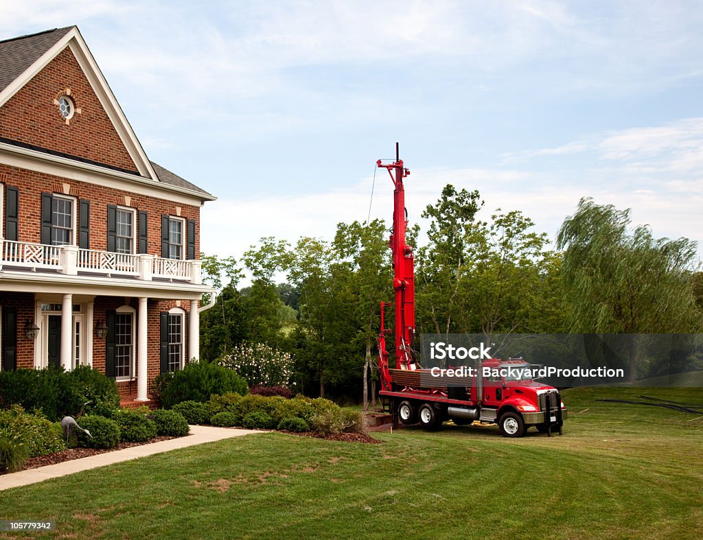 Red truck drilling into the yard Drilling for geothermal power system in suburban yard Drill Stock Photo