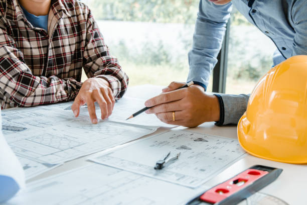 istock Concept architects,engineer holding pen pointing equipment architects On the desk with a blueprint in the office, Vintage, Sunset light.Selective Focus 1057800260