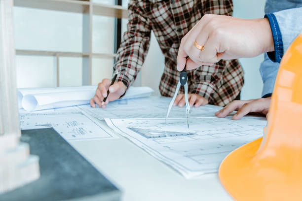 istock Concept architects,engineer holding Circus pointing equipment architects On the desk with a blueprint in the office Vintage Sunset light.Selective Focus 1057802056