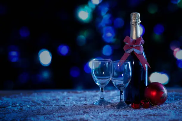 Image of champagne bottle and glasses with Christmas ball ornament over snow