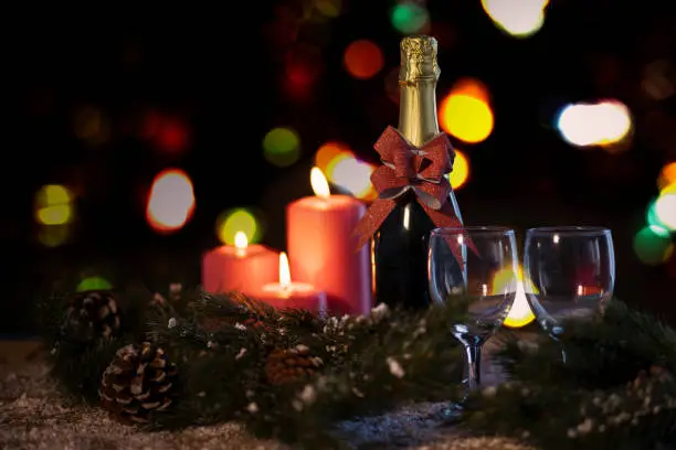 Close up of two glasses and champagne bottle with Christmas candles on the table
