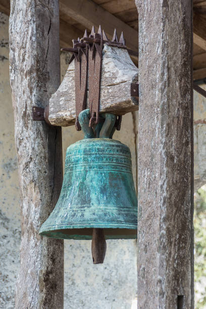 istock Ancient bronze bell covered with patina hanging from a wooden structure 1057824618
