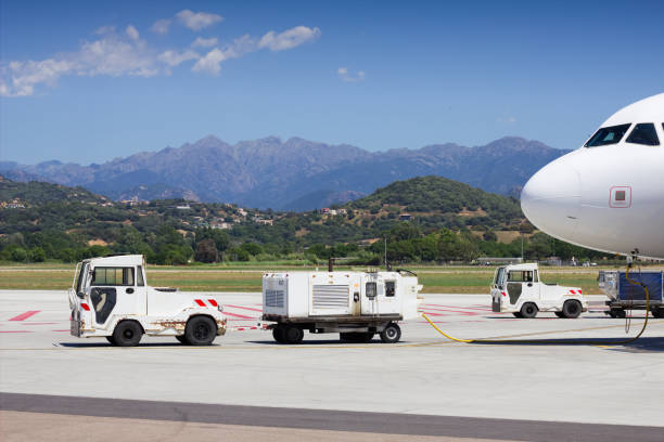 Airport vehicles towing white modern aircraft on the parking lot. Airport ground operation. Ajaccio, Corsica Airport. stock photo