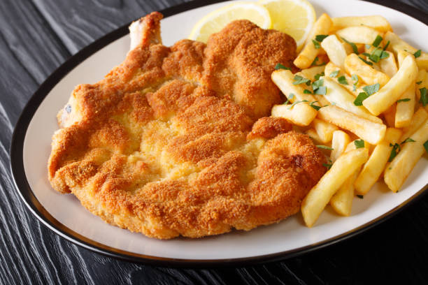 Veal alla Milanese (cotoletta alla milanese) with French fries close-up on a plate. Horizontal Veal alla Milanese (cotoletta alla milanese) with French fries close-up on a plate on a table. Horizontal scaloppini stock pictures, royalty-free photos & images