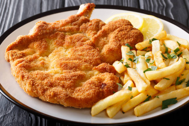 Milanese Beef cutlet breaded with lemon and French fries close-up. horizontal Milanese Beef cutlet breaded with lemon and French fries close-up on a plate. horizontal scaloppini stock pictures, royalty-free photos & images