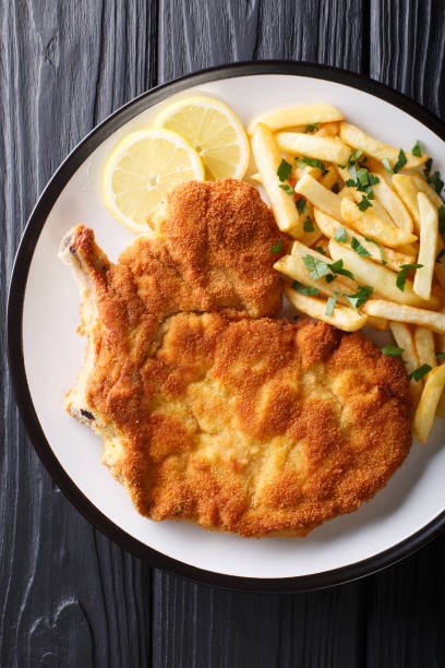 smażony kotlet cielęcy milanese z cytryną i frytkami z bliska. pionowy widok z góry - cutlet schnitzel french fries scaloppini zdjęcia i obrazy z banku zdjęć