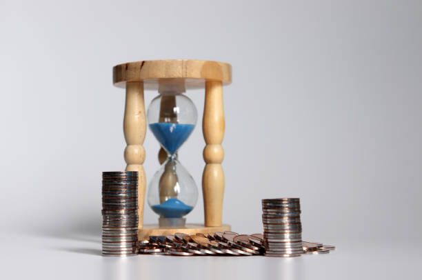 istock Hourglass and pile of coins. 1057833236