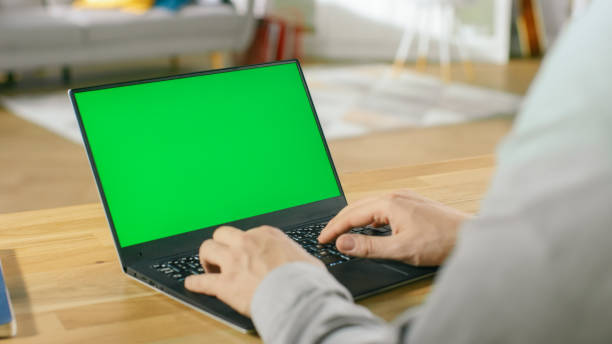 istock Professional Freelancer Works on a Laptop with Green Mock-up Screen while Sitting at the Desk in His Cozy Living Room. 1057834560