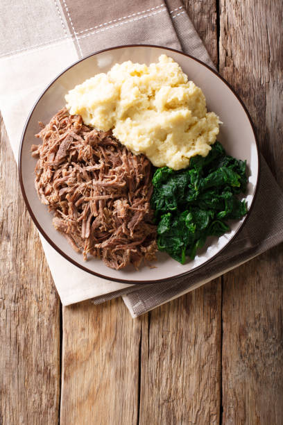istock Botswana cuisine: seswaa beef stew with pap porridge and spinach close-up on a plate. Vertical top view 1057836322