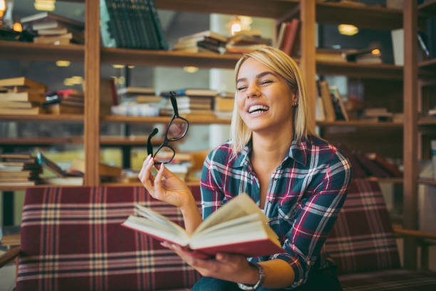 istock Cheerful female student enjoying book reading in library 1057838114