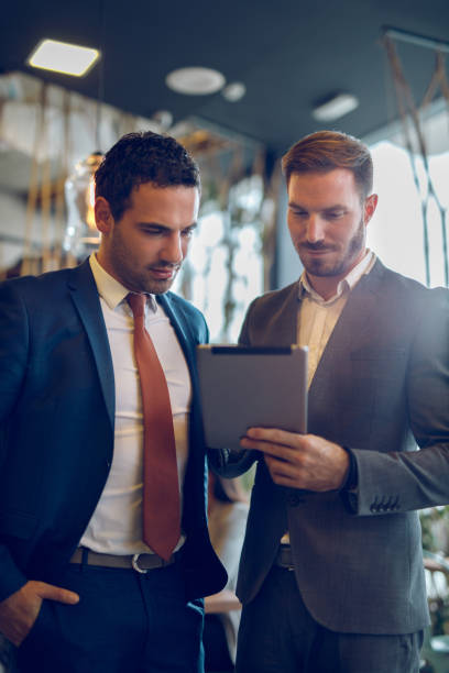 istock Two young businessmen discussing business strategy using digital tablet 1057841836