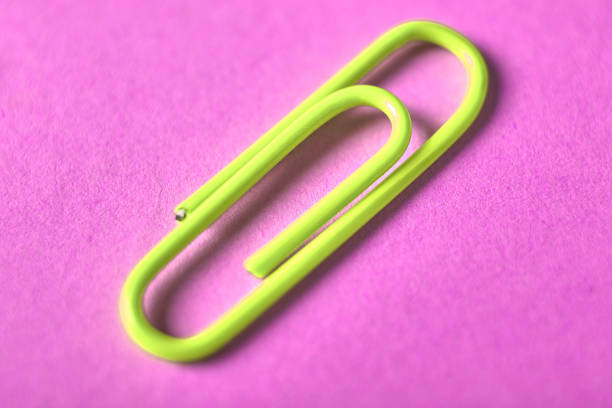 istock One yellow paper clip isolated on violet background, close up, copy space. Top view, flat lay. Back to school, college, education concept 1057844904