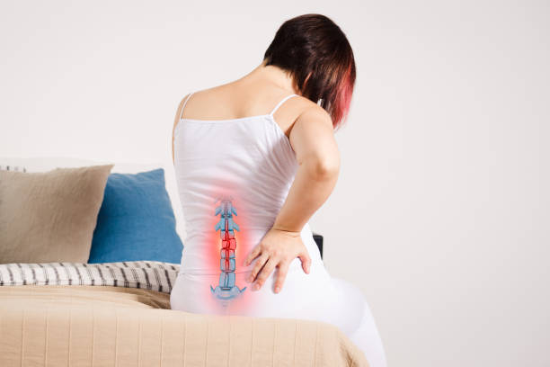 Pain in the spine, woman with backache at home, injury in the lower back Pain in the spine, woman with backache at home, injury in the lower back, photo with highlighted skeleton coccyx photos stock pictures, royalty-free photos & images