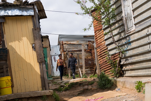 A young African couple walking together through the alleys of the rural township
