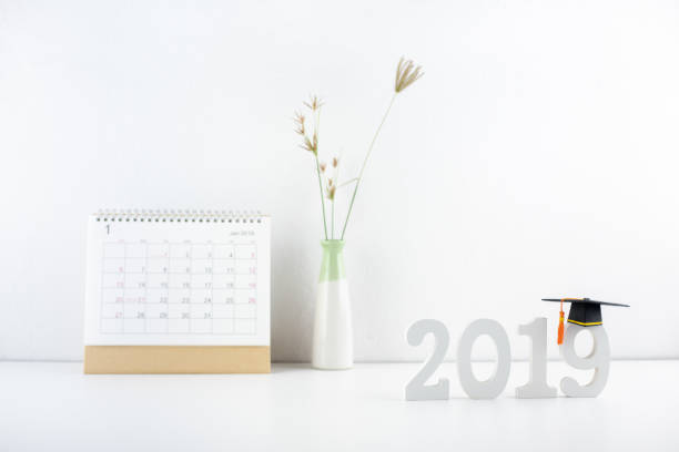 2019 happy new year / graduate study abroad program, time schedule arrangement, education concept : Black graduation cap of success on number 2019 white wood cut on student desk, pupil studying table