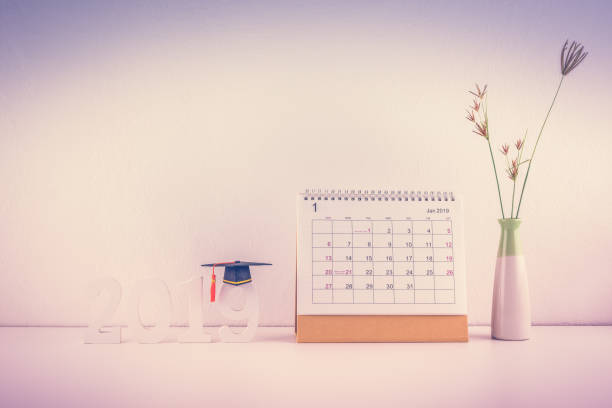 istock 2019 happy new year / graduate study abroad program, time schedule arrangement, education concept : Black graduation cap of success on number 2019 white wood cut on student desk, pupil working table 1057857038