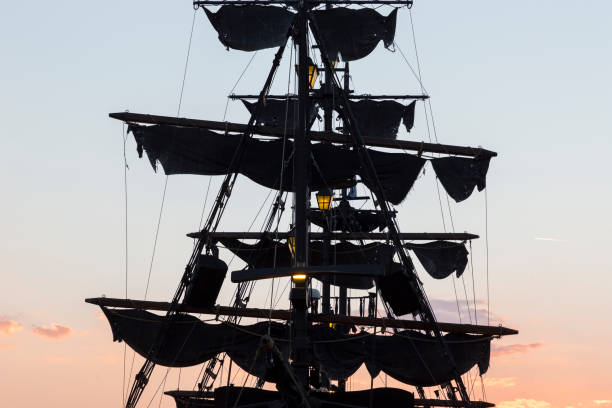 Bridgetown, Barbados - November 20, 2011: a woman and a man on the wharf at sunset. The Jolly Roger I is moored: tomorrow it will sail for another traditional excursion by sea.