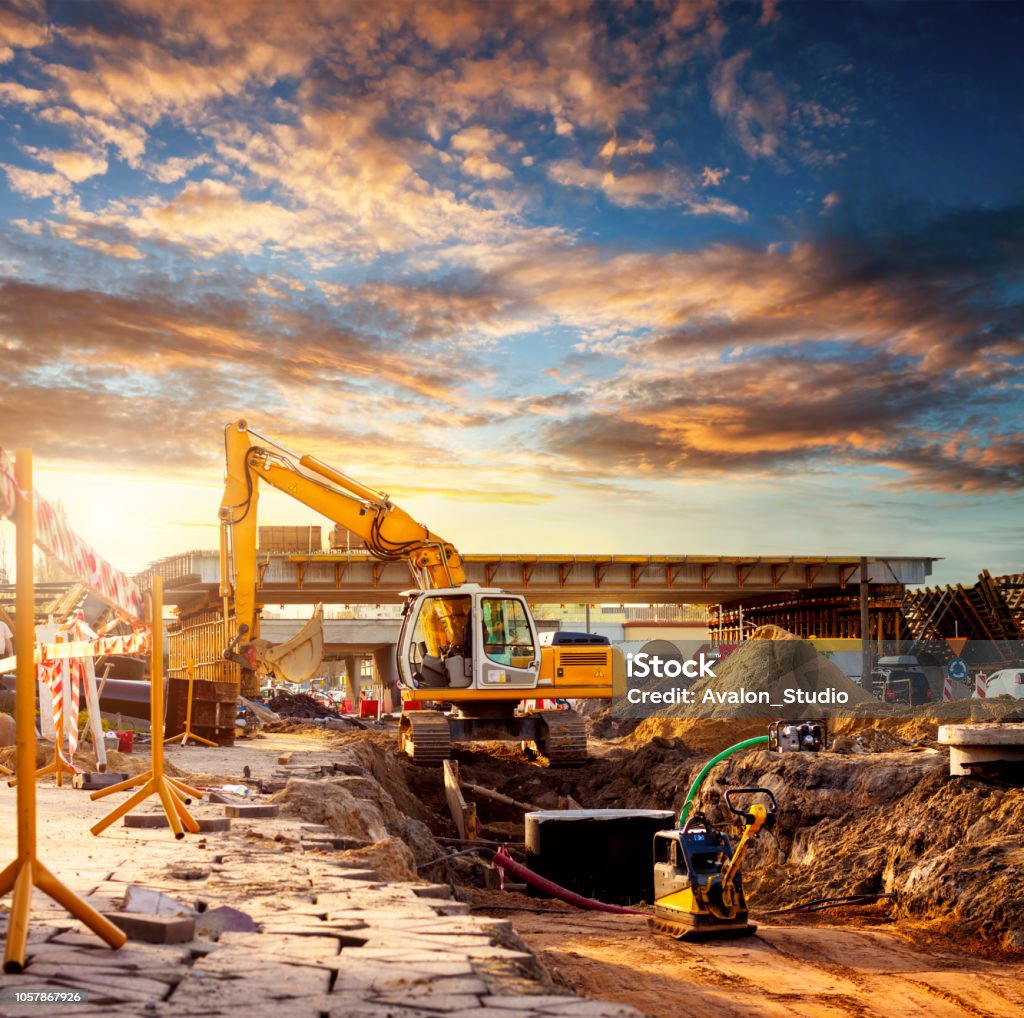 Excavator on a road construction site Large excavator caterpillar on a construction site. Excavator on a road construction site. Construction Site Stock Photo