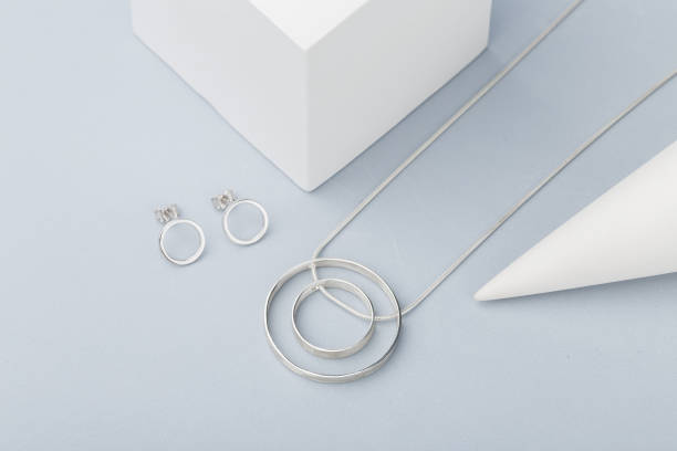 istock Minimalist geometric silver necklace and circle stud earrings on gray background 1057881244