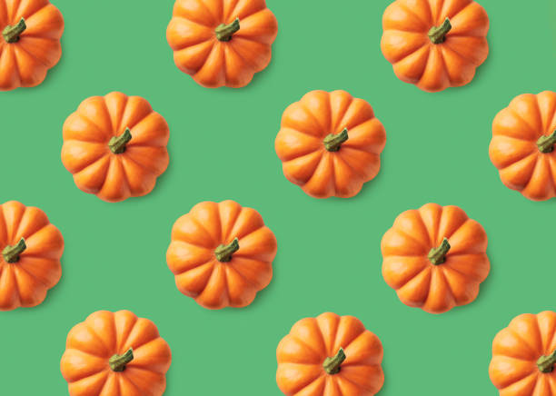 istock Colorful pattern of orange pumpkins on green background 1057881904