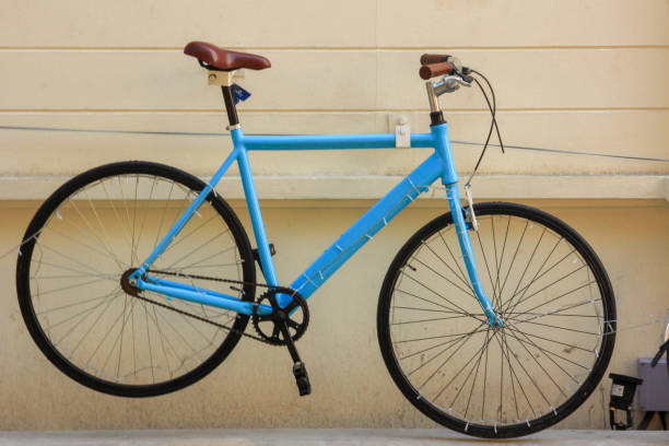 istock Blue bicycle hanging on pale yellow cement wall 1057888182