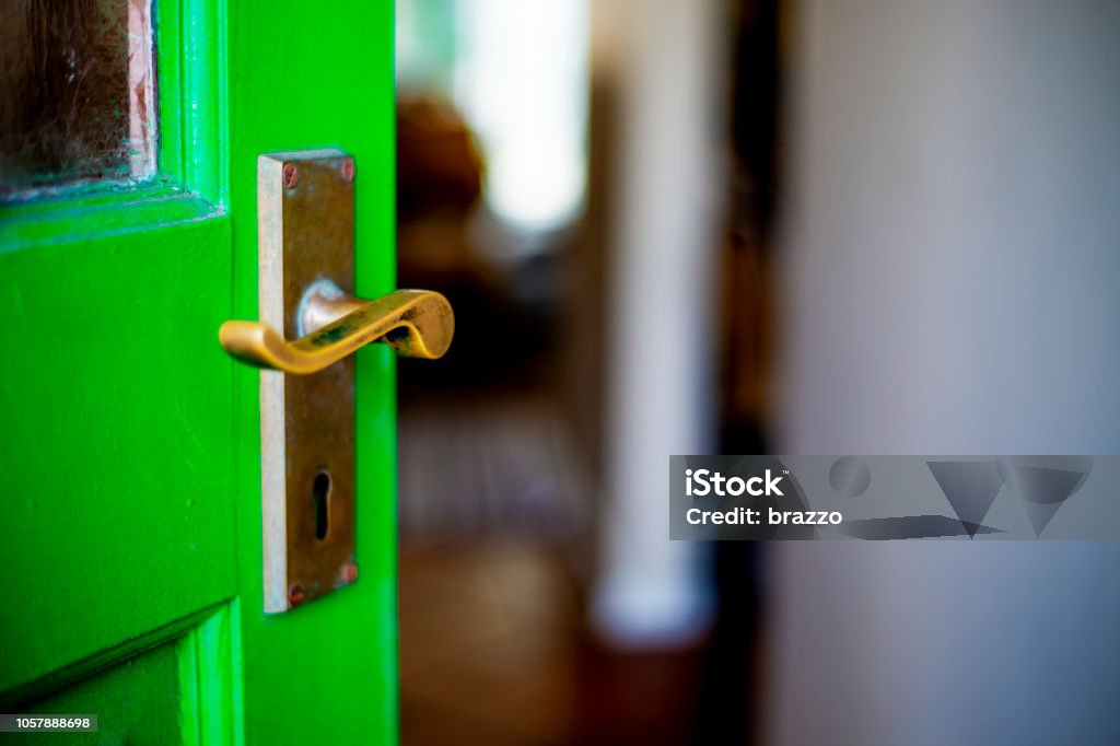 Green door open ajar onto entrance hall Front Door Stock Photo