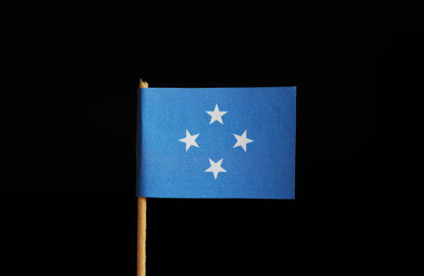 un drapeau national des états fédérés de micronésie sur un bâton en bois sur fond noir. la fédération fait partie de l’océanie - federated photos et images de collection