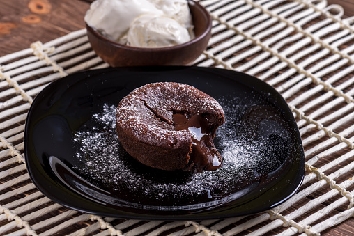 Concept: restaurant menus, healthy eating, homemade, gourmands, gluttony. White plate with chocolate fondant and ice cream on a messy vintage wooden background.