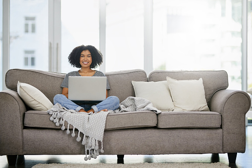 Shot of an attractive young woman using a laptop on the sofa at home