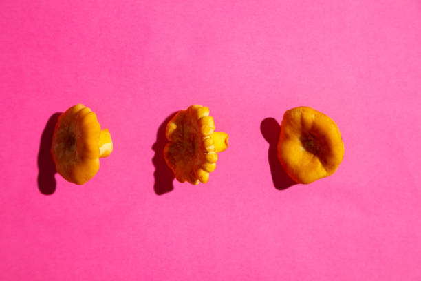 Three orange mushrooms in horizontal row on pink background