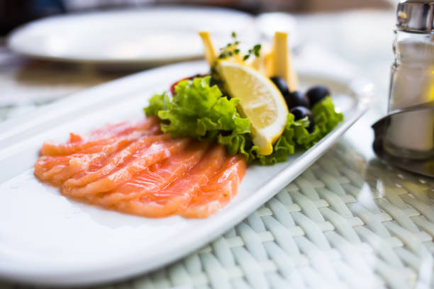 istock sliced smoked salmon served with lemon slices on white plate 1057912544