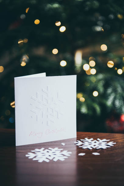 istock Embossed snowflake Christmas card displays on table against Christmas tree background 1057913196
