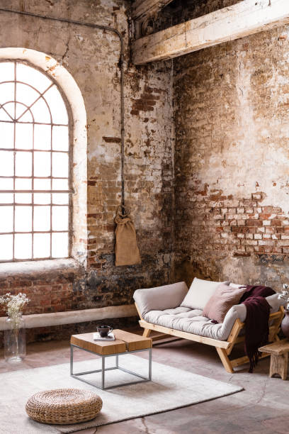 istock Pouf and table on rug in front of beige settee in spacious loft interior with window. Real photo 1057915272