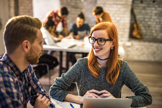 istock Happy redhead colleagues communicating while working in the office. 1057915796
