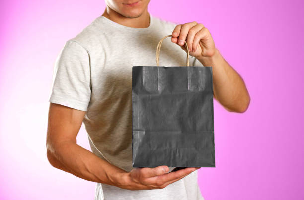 istock Man holding a black gift bag. Close up. Isolated background 1057920564