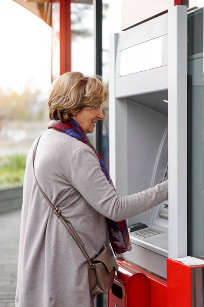 istock Senior woman using ATM in the city 1057920926