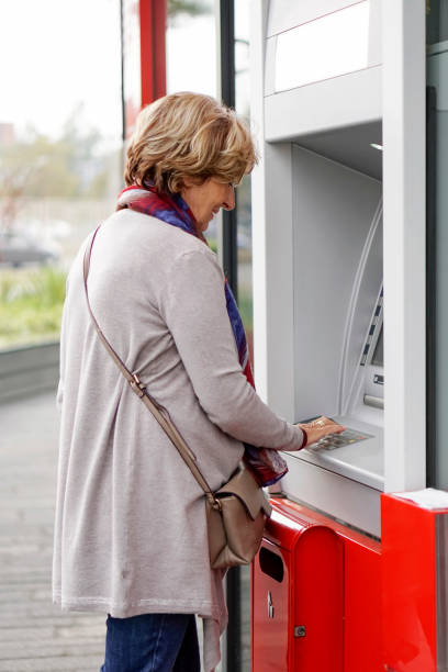 istock Senior woman using ATM in the city 1057920938