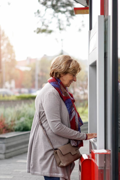 istock Senior woman using ATM in the city 1057921006