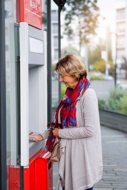 istock Senior woman using ATM in the city 1057921036